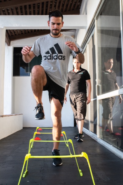 Atleta realizando entrenamiento de alta intensidad con movimientos pliométricos bajo supervisión profesional